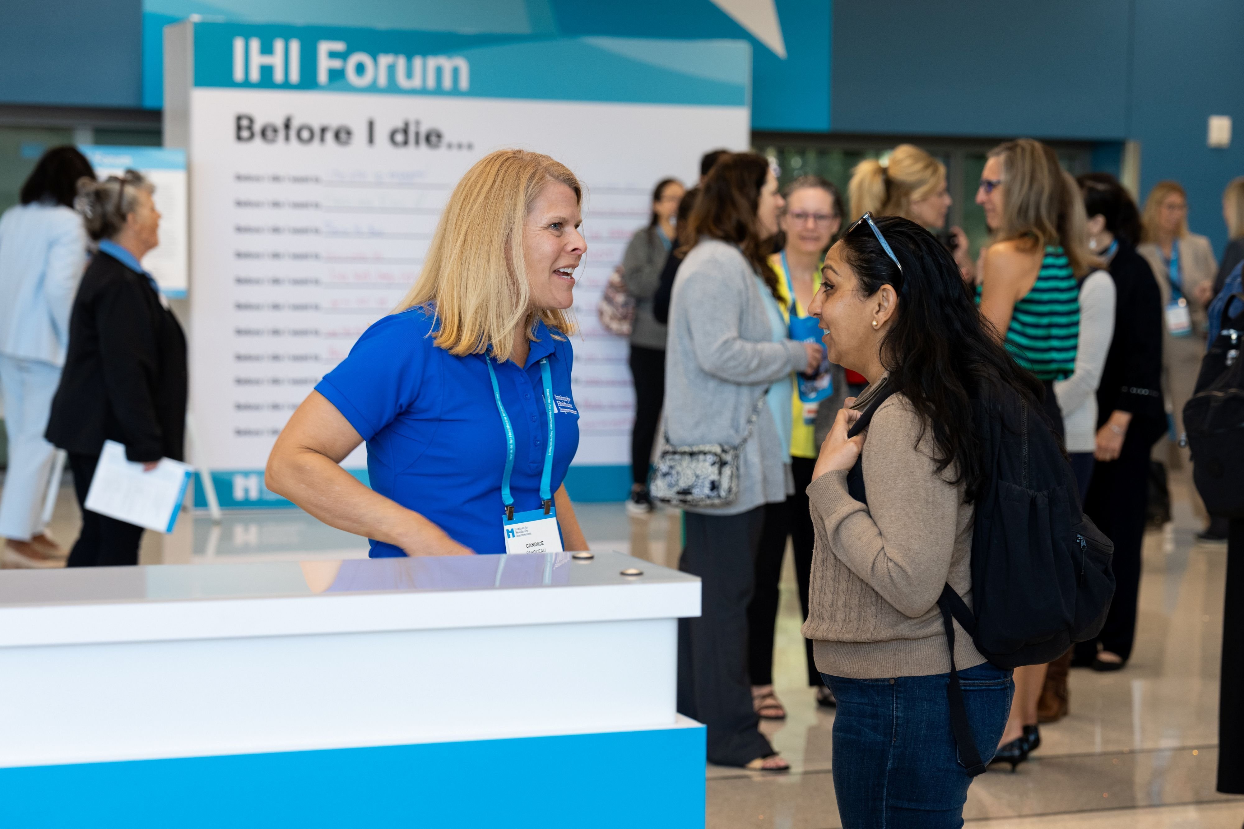 IHI staff member speaking with an attendee at the information booth.