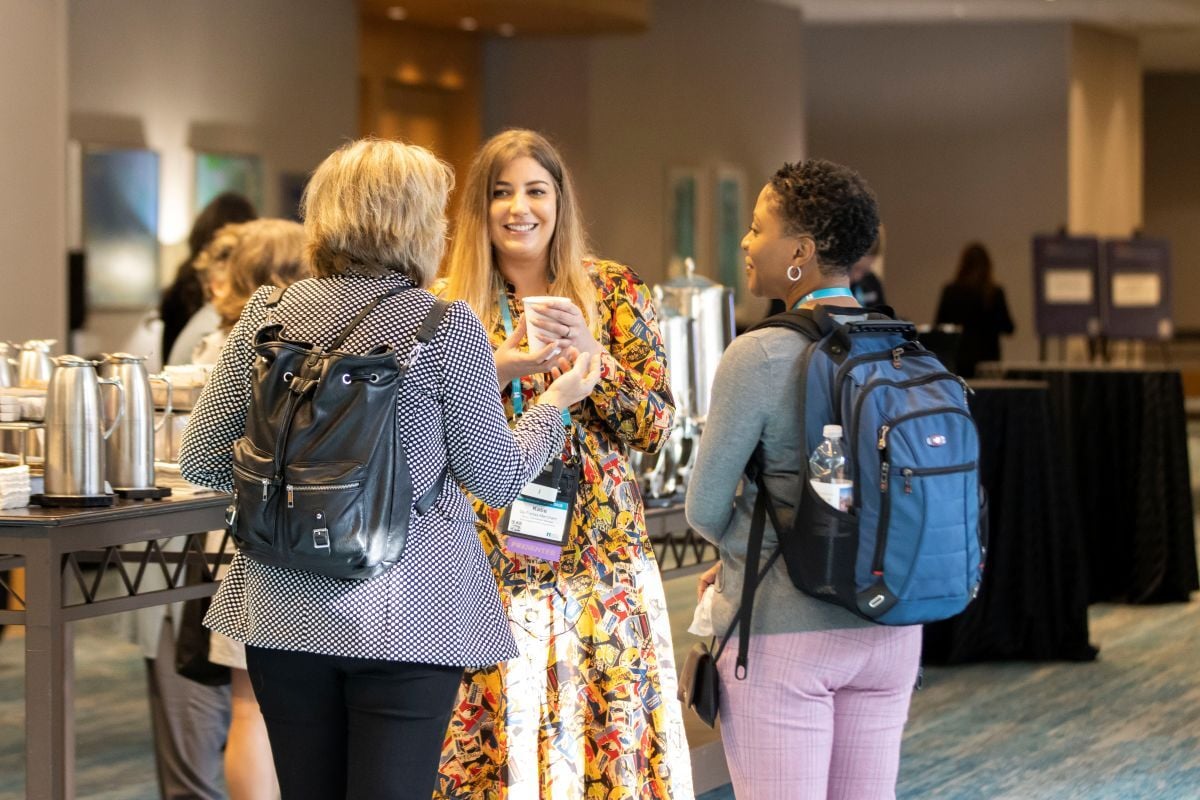 3 conference attendees talking to each other next to the conference breakfast tables