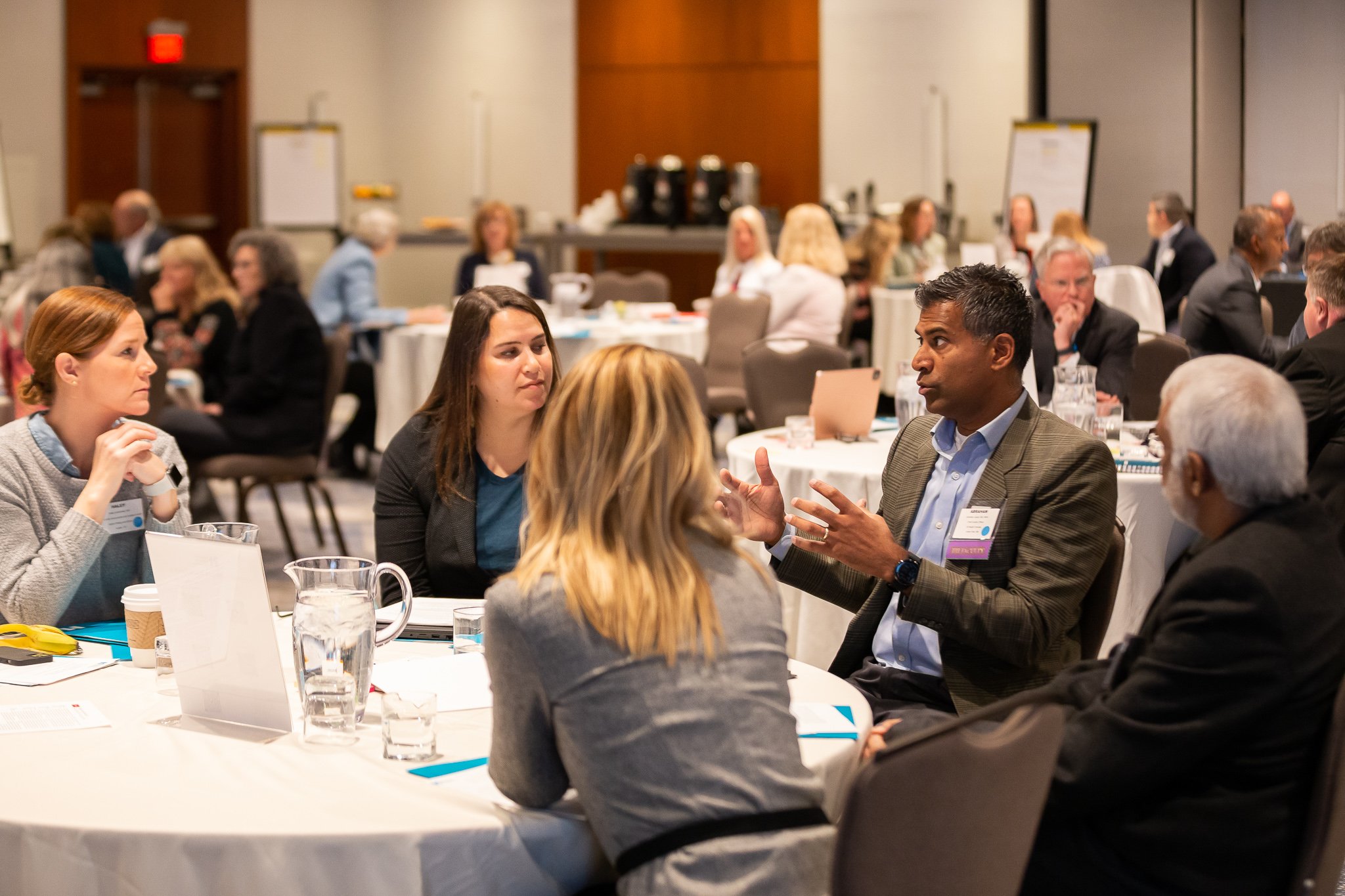 A group of conference attendees talking at a circular table.