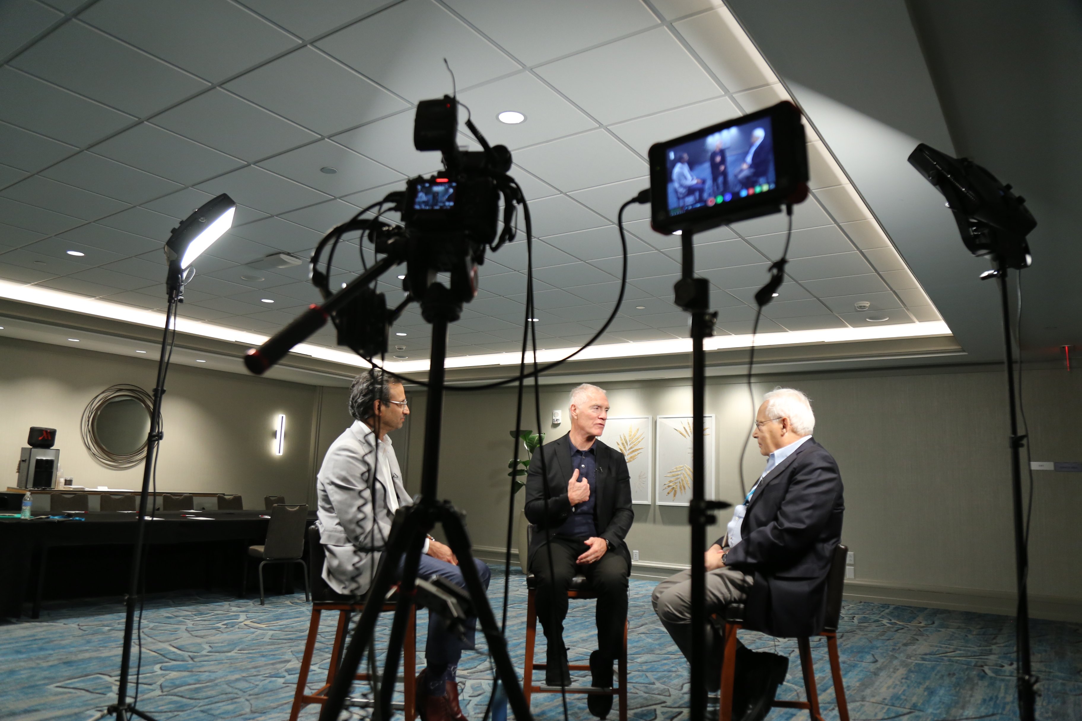 A behind the scenes image of Don Berwick and Kedar Mate interviewing a guest during a taping of the Turn on the Lights Podcast.